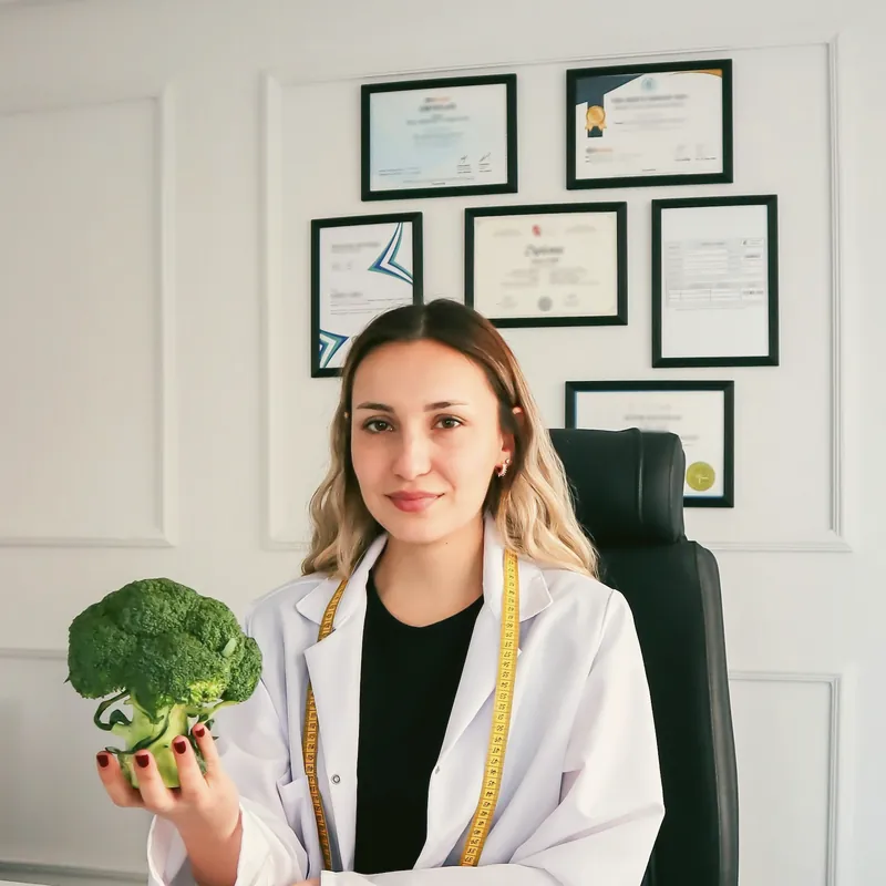 Nutricionista en su consultorio con un brócoli en la mano